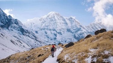 Hyperrealistic image of a trekker pondering a daunting pass in Nepal's Annapurna Circuit at dawn.