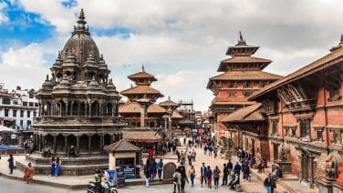 Alt text: Vibrant Kathmandu at dawn, with bustling streets, intricate architecture, and Himalayan backdrop.