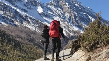 Adventurer at Annapurna Circuit's summit during sunrise, ethereal mountain glow, inspiring vast landscape.