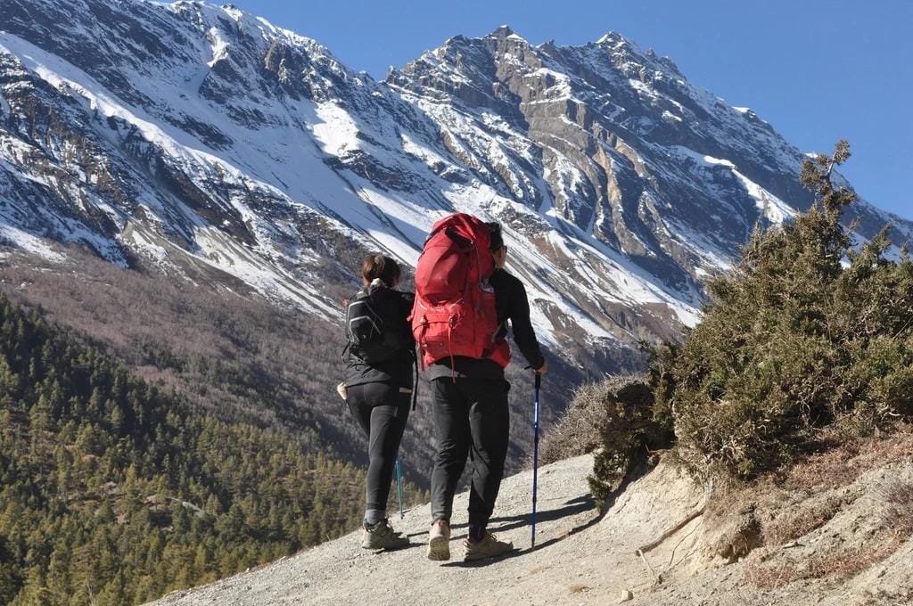 Adventurer at Annapurna Circuit's summit during sunrise, ethereal mountain glow, inspiring vast landscape.
