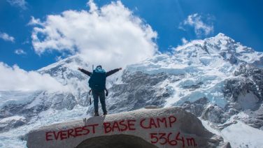 Trekker standing at Everest Base Camp with Himalayan peaks in the background, Nepal trekking adventure